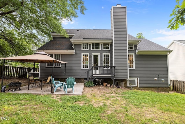 back of house featuring an outdoor fire pit, a gazebo, a chimney, a patio, and a shingled roof