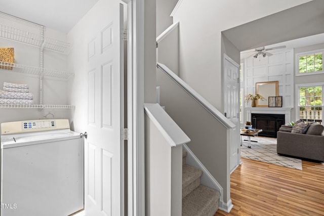 laundry area featuring washer / clothes dryer, ceiling fan, light wood finished floors, and a fireplace