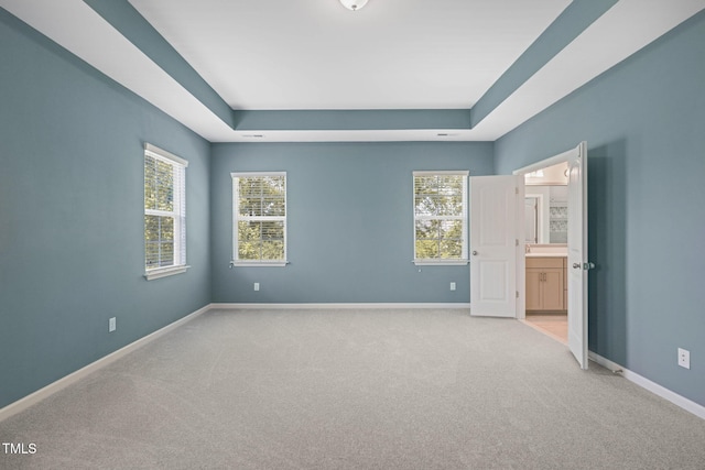 1013 Poppy Fields Ln, Wake Forest, NC 27587 - unfurnished bedroom featuring a tray ceiling, light colored carpet, and ensuite bath