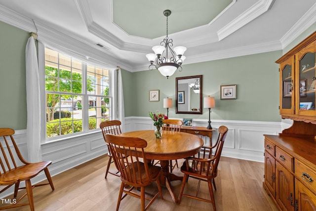 232 Shady Hollow Ln, Garner, NC 27529 - dining area with a raised ceiling, light wood finished floors, a wainscoted wall, a chandelier, and crown molding