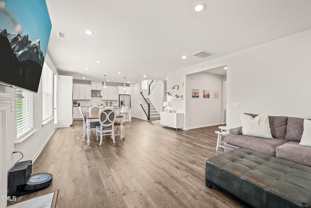 living area with stairs, wood finished floors, recessed lighting, and baseboards
