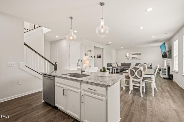 kitchen featuring a sink, dark wood-style floors, stainless steel dishwasher, a center island with sink, and white cabinetry