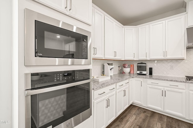kitchen featuring stainless steel oven, built in microwave, white cabinetry, and tasteful backsplash