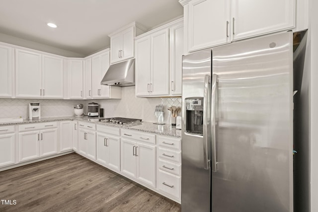 kitchen featuring stainless steel appliances, under cabinet range hood, white cabinets, decorative backsplash, and light stone countertops