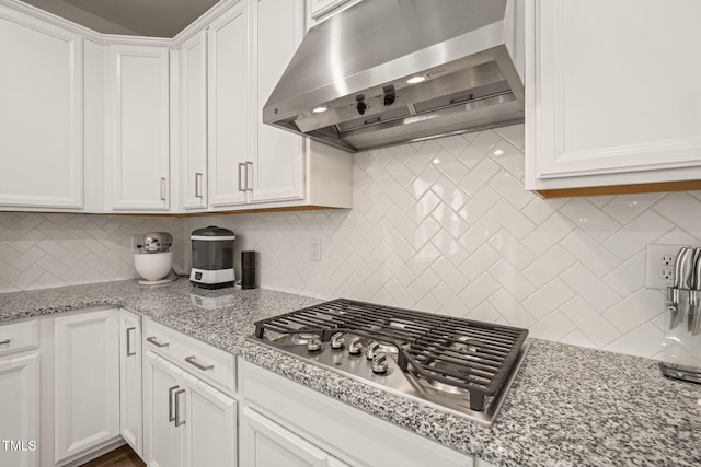 kitchen with extractor fan, stainless steel gas stovetop, tasteful backsplash, white cabinetry, and light stone countertops