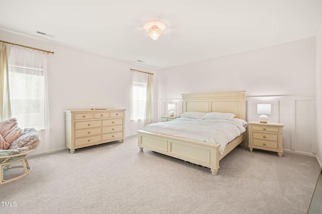 bedroom featuring light colored carpet and a decorative wall