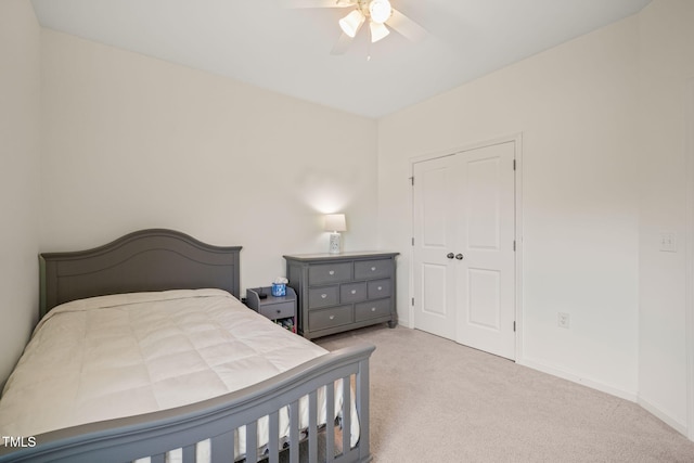 bedroom with light colored carpet, ceiling fan, baseboards, and a closet