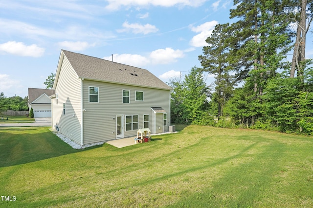 back of property featuring a yard, a detached garage, a patio, and a shingled roof