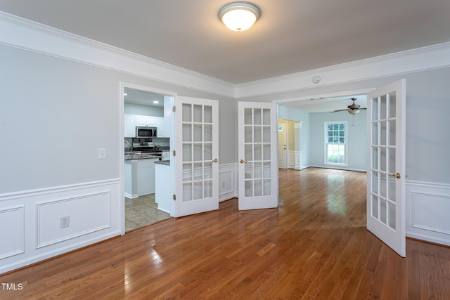 9305 Dominion Blvd, Raleigh, NC 27617 - spare room featuring french doors, ornamental molding, wood finished floors, a ceiling fan, and wainscoting