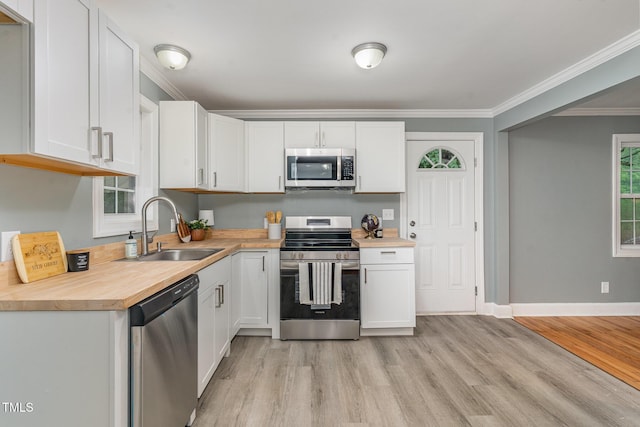 4420 W River Rd, Franklinton, NC 27525 - kitchen featuring appliances with stainless steel finishes, a sink, white cabinets, light wood-style floors, and ornamental molding