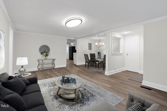 313 W Church St, Angier, NC 27501 - living area featuring a chandelier, ornamental molding, wood finished floors, baseboards, and electric panel