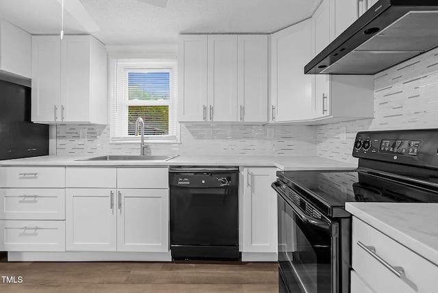 313 W Church St, Angier, NC 27501 - kitchen featuring black appliances, under cabinet range hood, a sink, white cabinetry, and wood finished floors