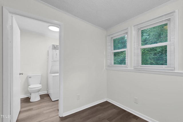 313 W Church St, Angier, NC 27501 - unfurnished bedroom featuring ornamental molding, wood finished floors, stacked washer / dryer, a textured ceiling, and baseboards