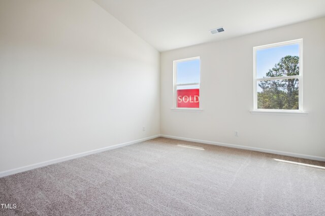 carpeted empty room with vaulted ceiling and baseboards