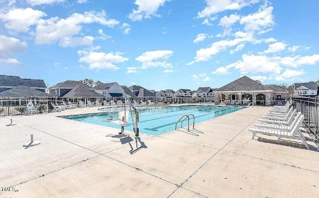 community pool featuring fence, a patio, and a residential view