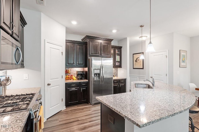 174 Walking Path Pl, Hillsborough, NC 27278 - kitchen with stainless steel appliances, a sink, light wood-style flooring, a kitchen bar, and decorative light fixtures
