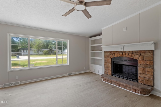 125 Hillcreek Dr, Parkton, NC 28371 - unfurnished living room with a textured ceiling, crown molding, a fireplace with raised hearth, ceiling fan, and light wood-style floors