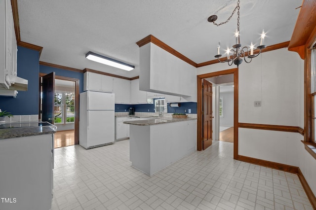 2610 N Main St, Tarboro, NC 27886 - kitchen with freestanding refrigerator, brick patterned floors, a peninsula, white cabinetry, and a chandelier