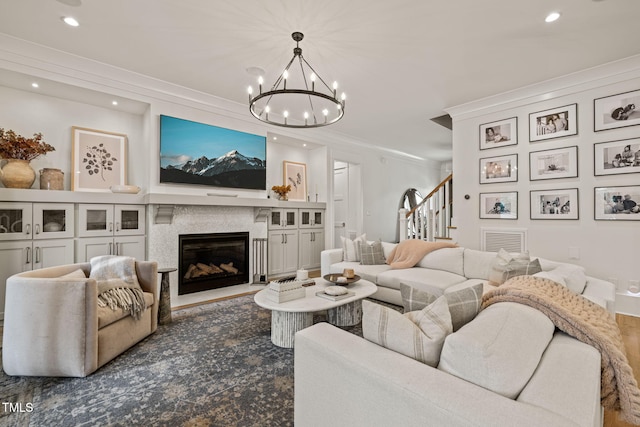 5308 Montclair Dr, Raleigh, NC 27609 - living room featuring recessed lighting, stairs, a chandelier, ornamental molding, and a glass covered fireplace