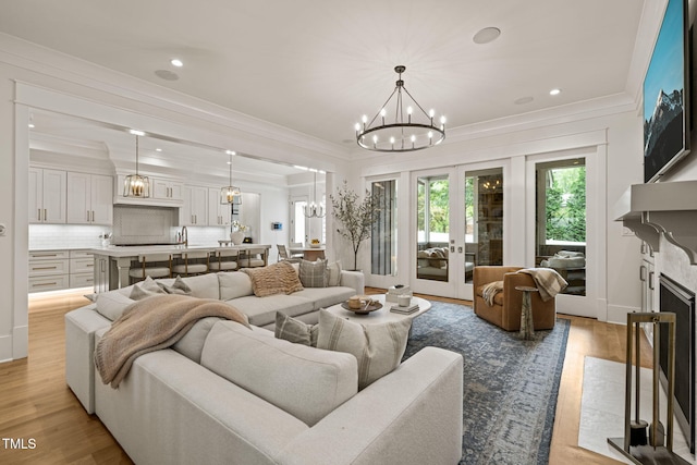 5308 Montclair Dr, Raleigh, NC 27609 - living room with a chandelier, wood finished floors, crown molding, recessed lighting, and a fireplace with flush hearth