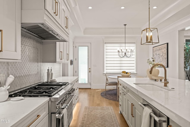 5308 Montclair Dr, Raleigh, NC 27609 - kitchen with stainless steel appliances, a sink, a chandelier, premium range hood, and light wood finished floors
