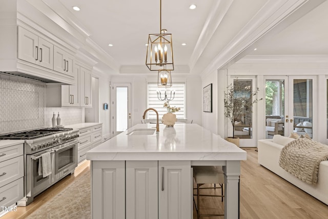 5308 Montclair Dr, Raleigh, NC 27609 - kitchen featuring a sink, range with two ovens, crown molding, a chandelier, and an island with sink