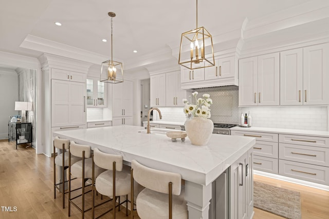 5308 Montclair Dr, Raleigh, NC 27609 - kitchen with white cabinets, a kitchen island with sink, tasteful backsplash, light wood-style flooring, and recessed lighting