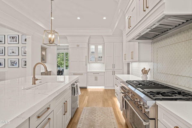 5308 Montclair Dr, Raleigh, NC 27609 - kitchen with stainless steel appliances, a sink, under cabinet range hood, white cabinetry, and light wood-type flooring