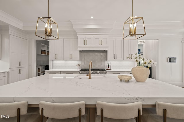 5308 Montclair Dr, Raleigh, NC 27609 - kitchen featuring a chandelier, tasteful backsplash, a kitchen island with sink, white cabinets, and recessed lighting