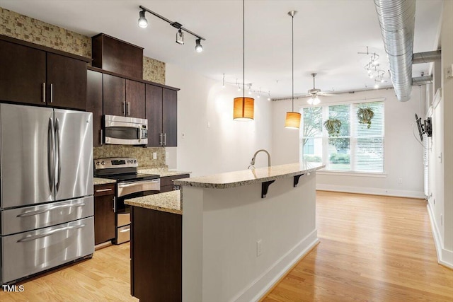 300 Finsbury St Unit 109, Durham, NC 27703 - kitchen with stainless steel appliances, a ceiling fan, a center island with sink, a breakfast bar, and light wood-style floors