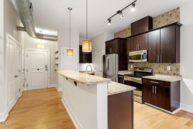 300 Finsbury St Unit 109, Durham, NC 27703 - kitchen with stainless steel appliances, light wood finished floors, backsplash, and dark brown cabinetry