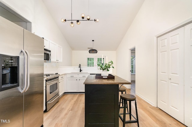 17 Crystal Oaks Ct, Durham, NC 27707 - kitchen featuring appliances with stainless steel finishes, a sink, light wood-type flooring, white cabinetry, and high vaulted ceiling
