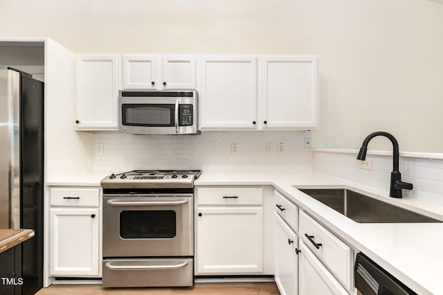 17 Crystal Oaks Ct, Durham, NC 27707 - kitchen featuring appliances with stainless steel finishes, a sink, tasteful backsplash, white cabinetry, and light countertops