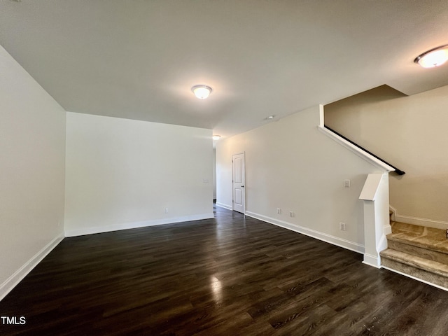 unfurnished living room with stairway, dark wood-style flooring, and baseboards