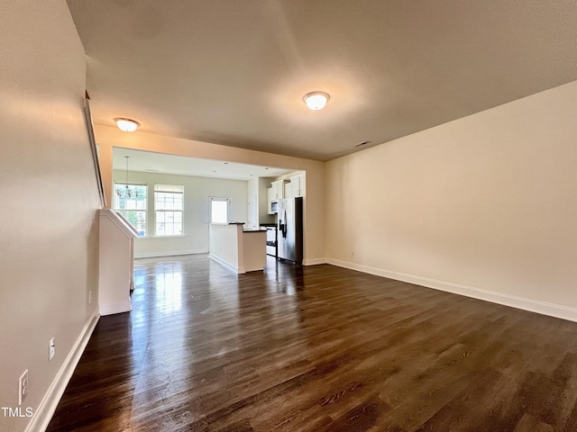 unfurnished living room featuring dark wood finished floors and baseboards