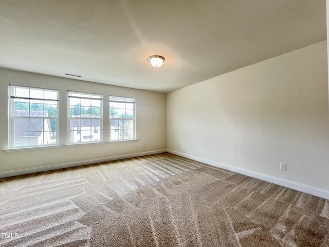 carpeted spare room featuring baseboards and healthy amount of natural light