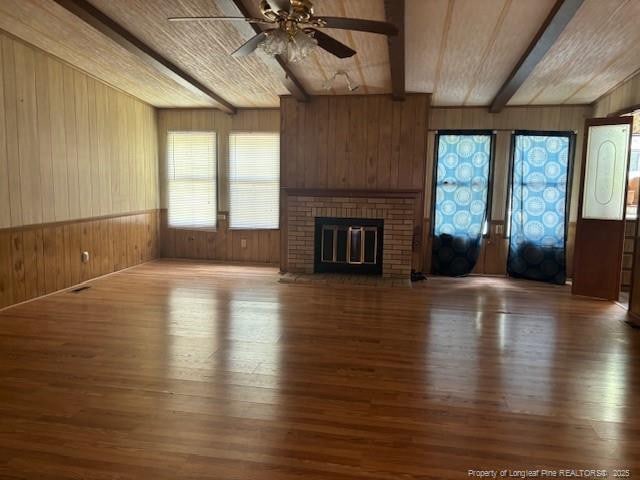 5689 NE Maxwell Rd NW, Stedman, NC 28391 - unfurnished living room featuring wood walls, wood-type flooring, a brick fireplace, ceiling fan, and french doors
