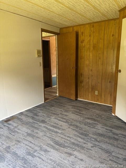 5689 NE Maxwell Rd NW, Stedman, NC 28391 - empty room featuring wood ceiling, wooden walls, and carpet floors