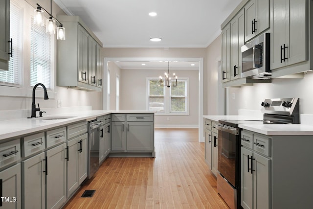 kitchen with stainless steel appliances, gray cabinets, a sink, light wood-type flooring, and a chandelier