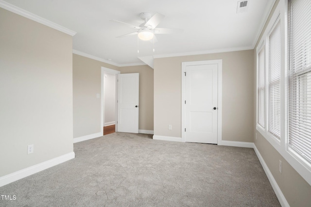 unfurnished bedroom featuring carpet floors, ornamental molding, baseboards, and a ceiling fan