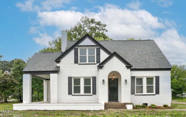 view of front of home featuring brick siding, a chimney, a shingled roof, and entry steps