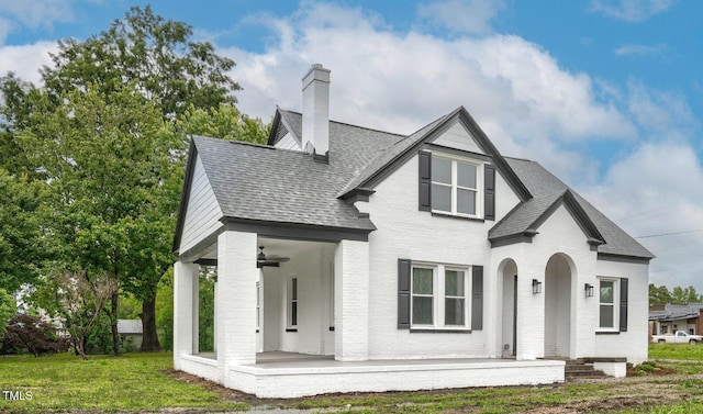 view of front facade with a porch, a chimney, roof with shingles, and brick siding