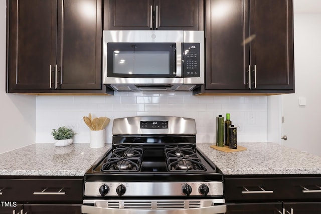 kitchen with appliances with stainless steel finishes, dark brown cabinetry, light stone countertops, and tasteful backsplash