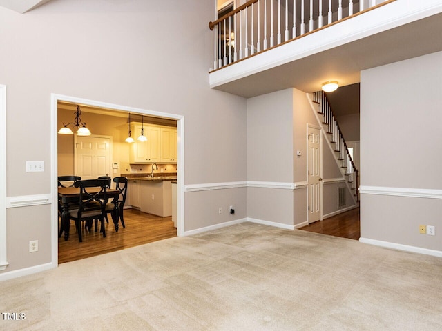 301 Monterey Ct, Benson, NC 27504 - carpeted living room featuring a towering ceiling, stairs, baseboards, and a sink