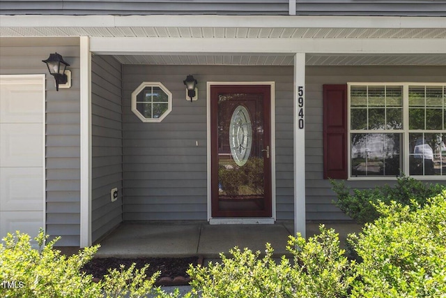 property entrance featuring covered porch and a garage
