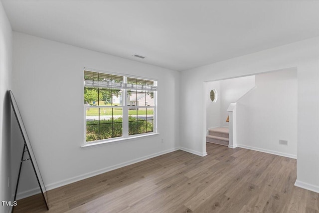 empty room with light wood-type flooring, stairway, and baseboards