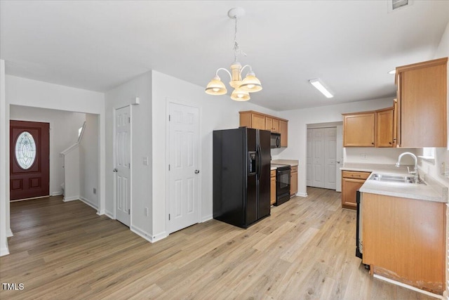 kitchen with black appliances, a sink, a chandelier, and light wood-style floors