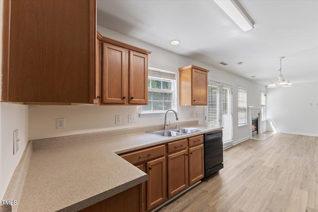 kitchen with black dishwasher, a sink, light wood-type flooring, light countertops, and brown cabinetry