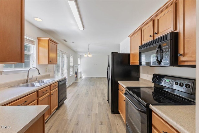 kitchen with black appliances, a sink, light wood finished floors, and light countertops
