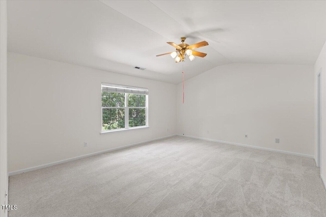 empty room featuring ceiling fan, vaulted ceiling, light colored carpet, and baseboards